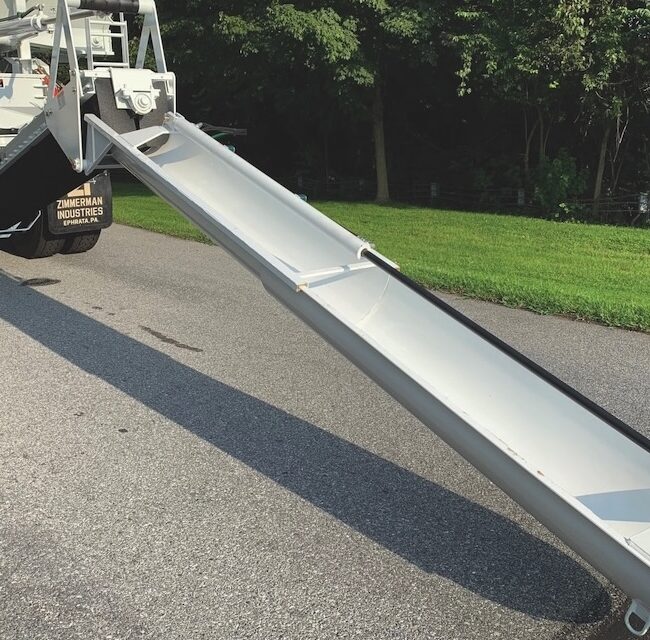 Power telescope chute system on the back of a volumetric concrete mixing truck.
