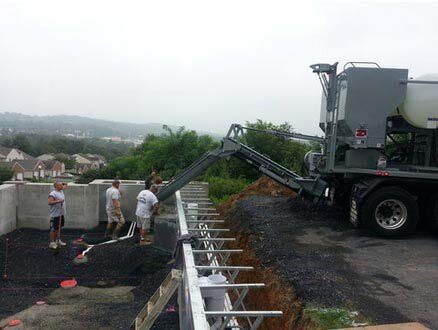 Construction site - concrete company is spreading fresh concrete as it pours from a volumetric concrete mixing truck. Concrete mixed on site.