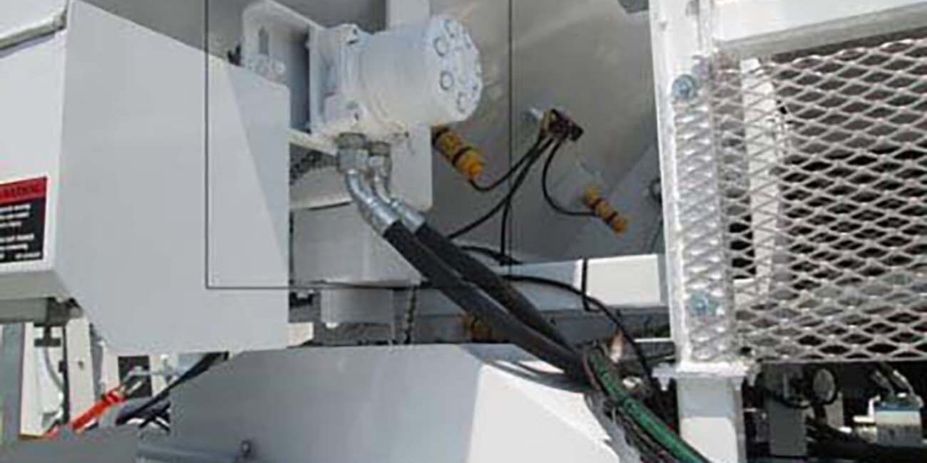 Close-up view of infinitely controlled hydraulic variable speed cement motor, and two independently controlled stone bin vibrators attached to the volumetric concrete mixing truck.