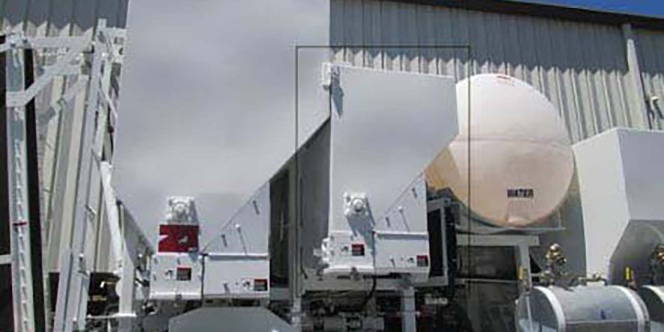 Side, close-up view of a volumetric concrete mixing truck - including a water tan, bin, and Pozzolan Bin.